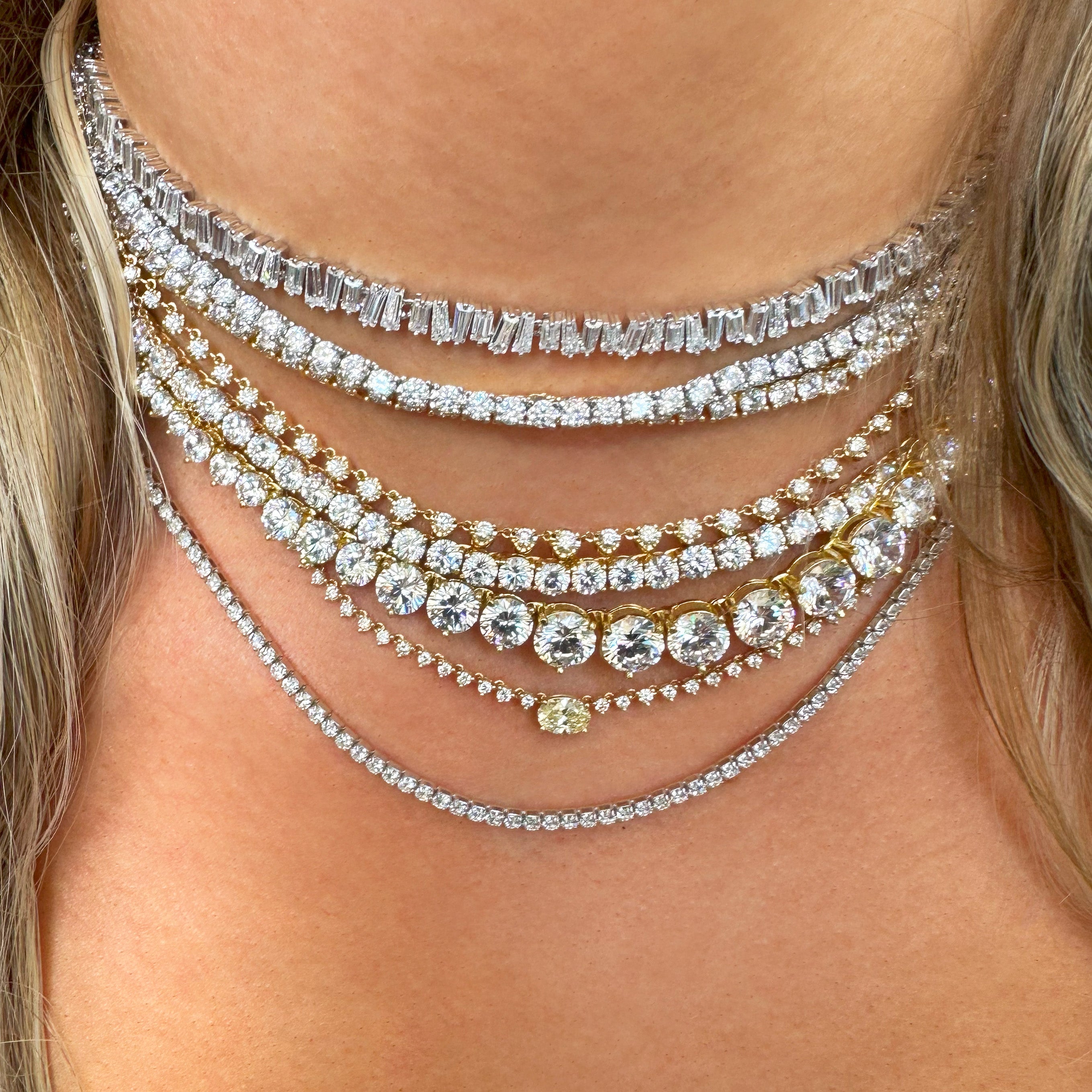Close-up of a woman wearing multiple diamond necklaces on a blurred background