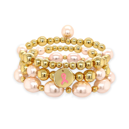 This stunning bracelet features gold beads and faux pink pearls. This gorgeous bracelet perfectly complements any ensemble, making it a versatile addition to your jewelry collection. Pair it effortlessly with other jewels and stay in vogue while making a meaningful impact.  Yellow Gold Beads and Faux Pink Pearls 3 Stretch Bracelet Set  Yellow Gold Plated 0.15", 0.20", 0.22", 0.30" Gold Beads 0.32", 0.40" x 0.50" Faux Light Pink Pearls Breast Cancer Awareness Ribbon Charm
