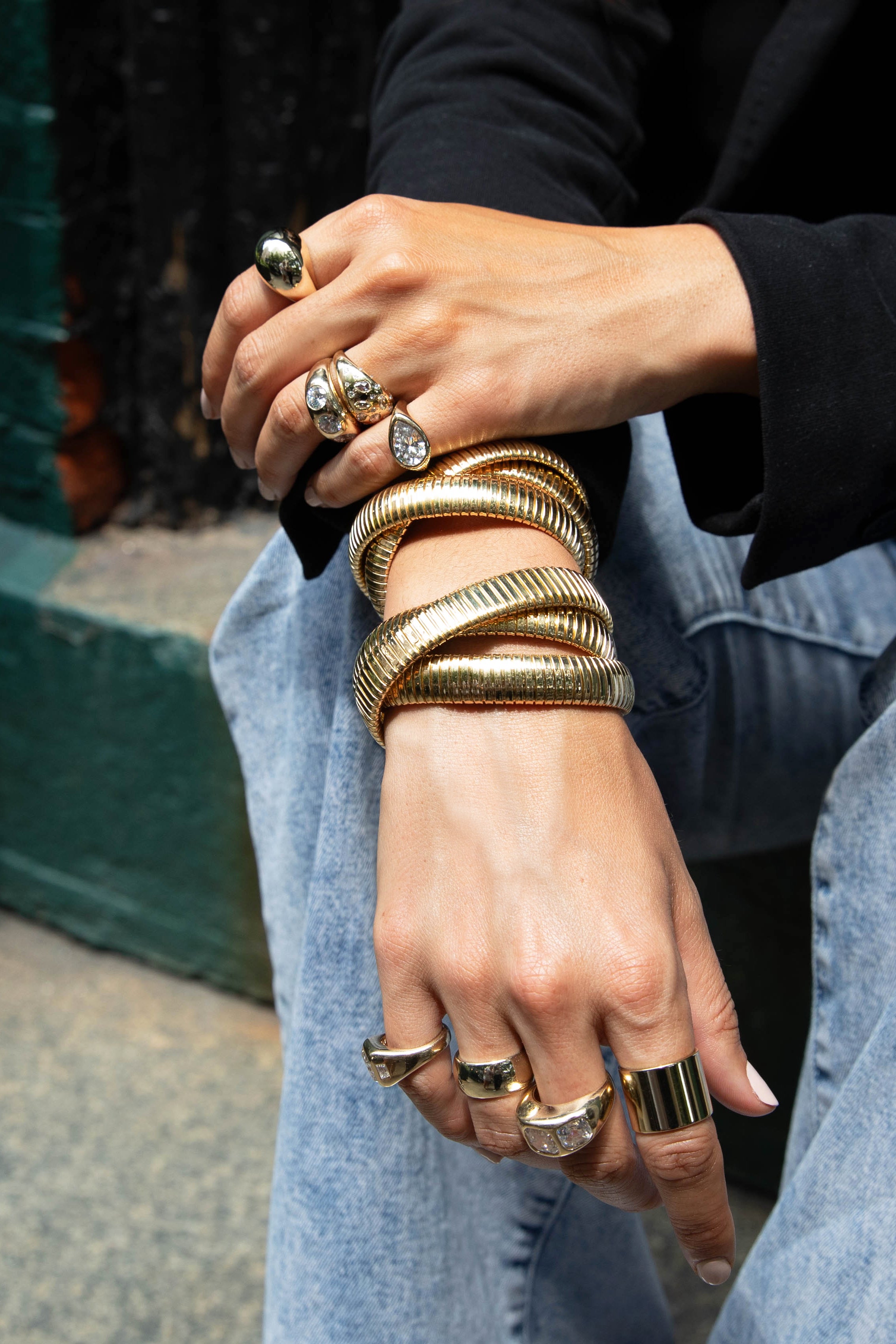 Image of hands decorated with multiple gold and cz rings and triple bracelet stack.