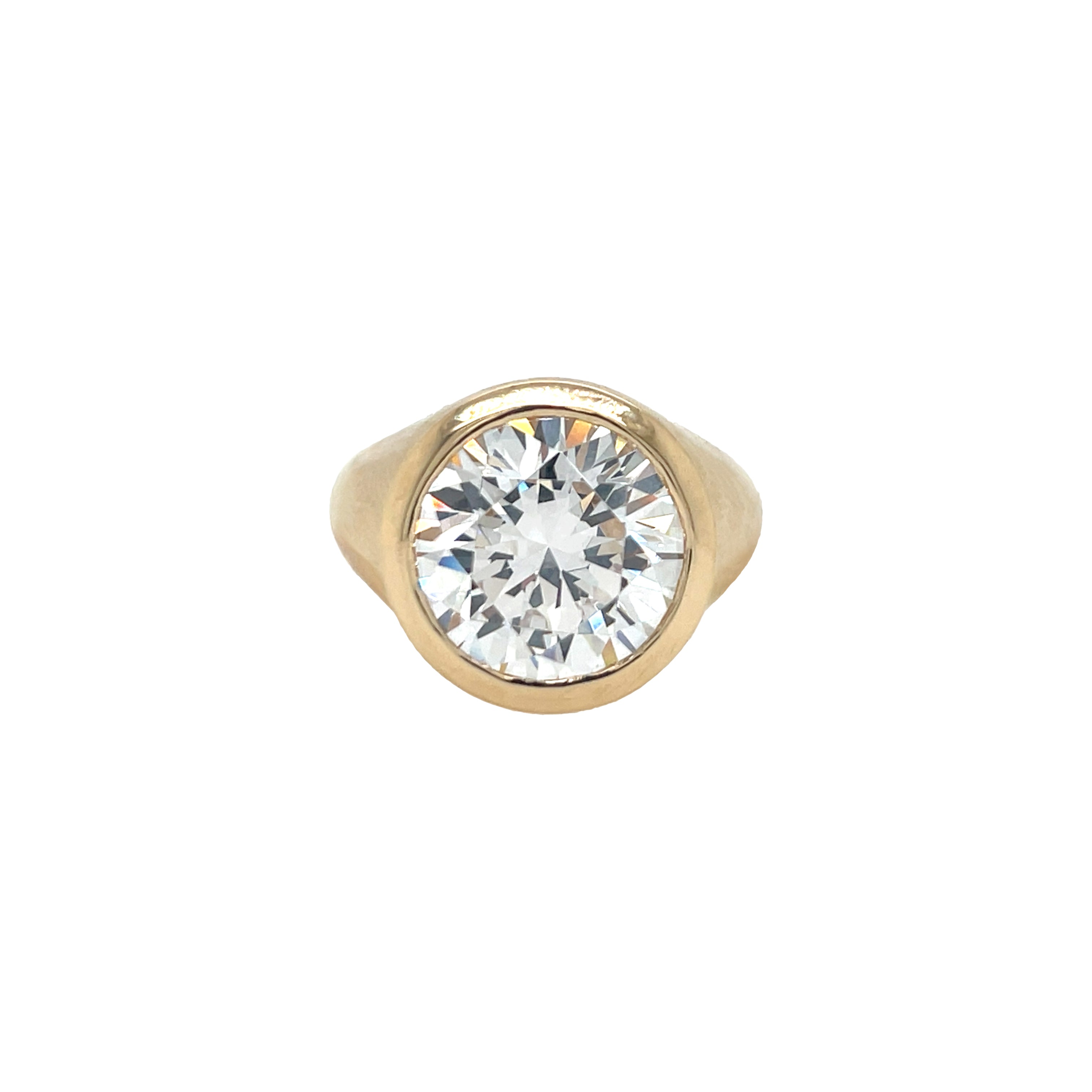 A round bezel ring with a large clear central stone, possibly a cubic zirconia, set in a gold-colored band.