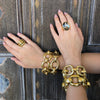 Multiple large chunky link bracelets worn with statement rings