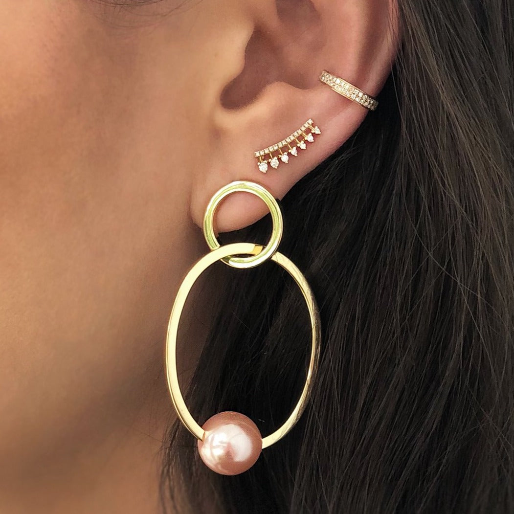 Woman wearing pave ear cuff with diamond crawler earring and open pearl hoops