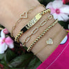 Yellow gold, diamond heart chain bracelets and beaded bracelet on a wrist.