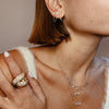 Woman wearing diamond V huggies with delicate collection of yellow gold chain link earrings and necklaces
