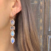 Diamond huggie earrings in woman's ear with diamond drop earrings