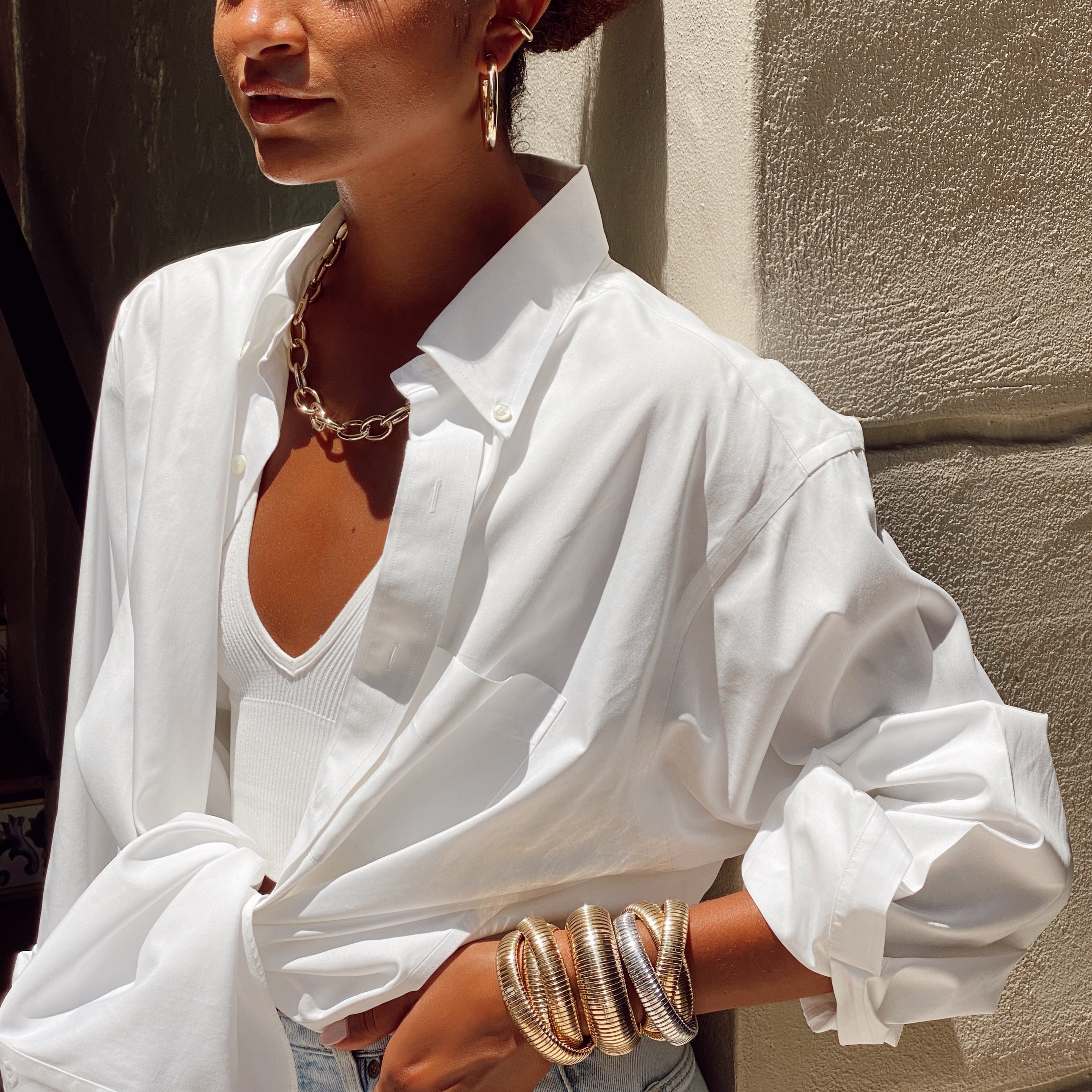 Woman wearing chunky link necklace with classic triple bracelets