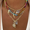 Multi charm necklace worn layered with yellow gold and rainbow beads