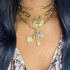 Multi charm necklace worn layered with yellow gold pendant necklace and chains