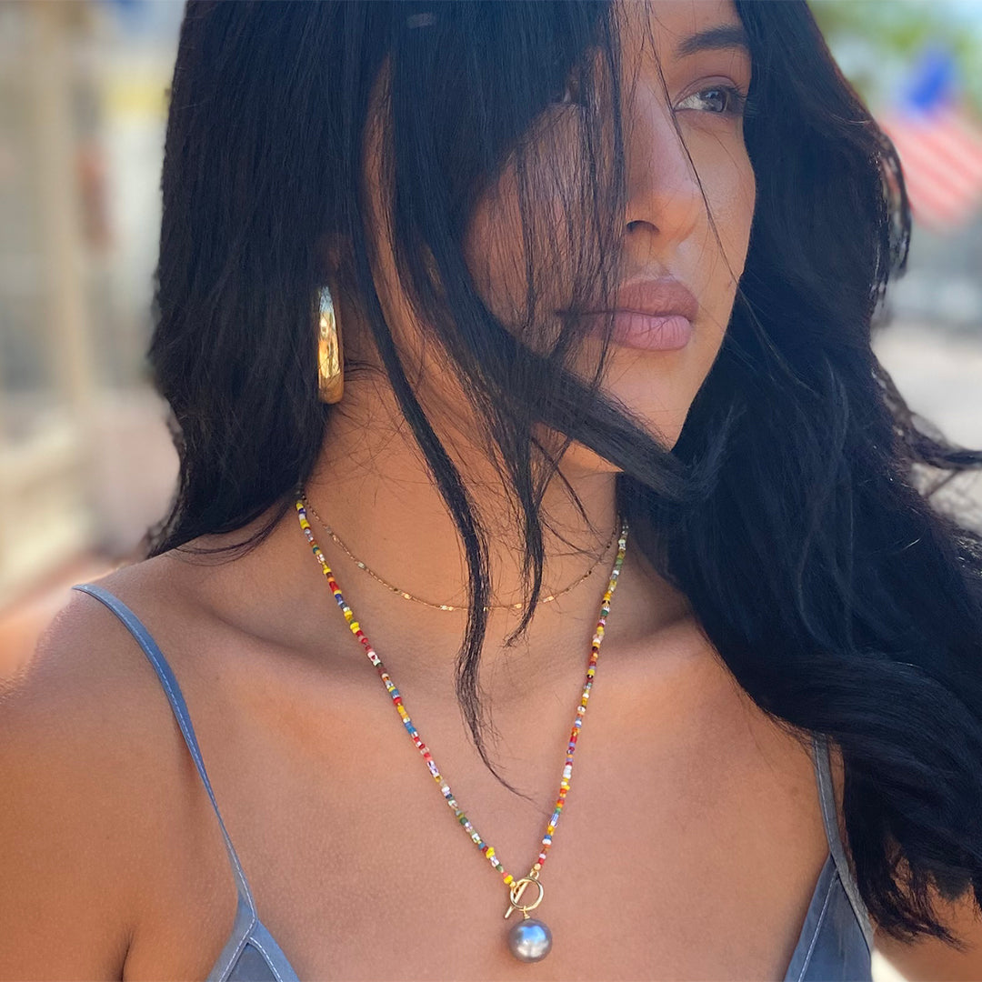 Woman wearing wide hoop earrings with colorful beaded necklace