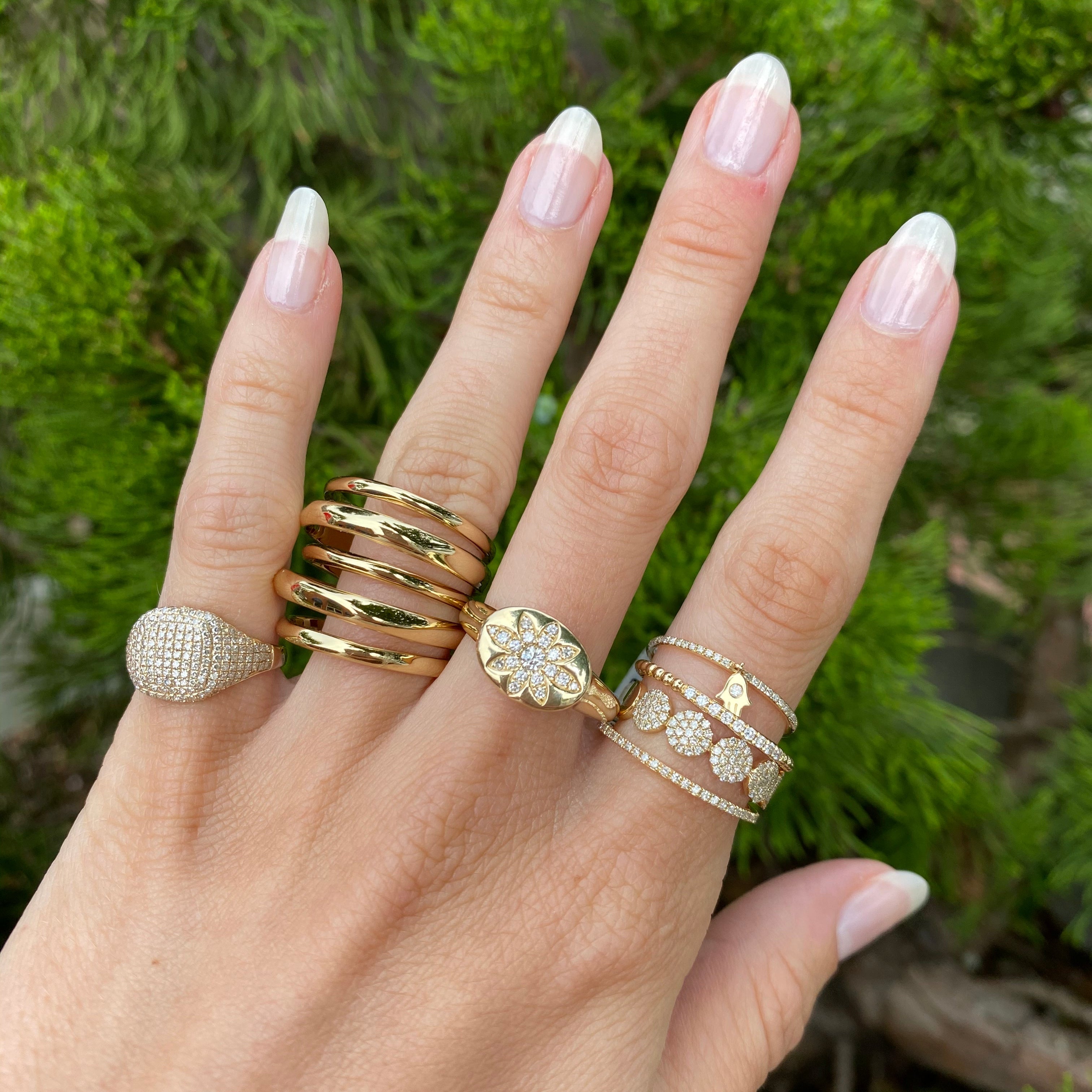 Diamond eternity band on woman's hand paired with other yellow gold and diamond pave rings