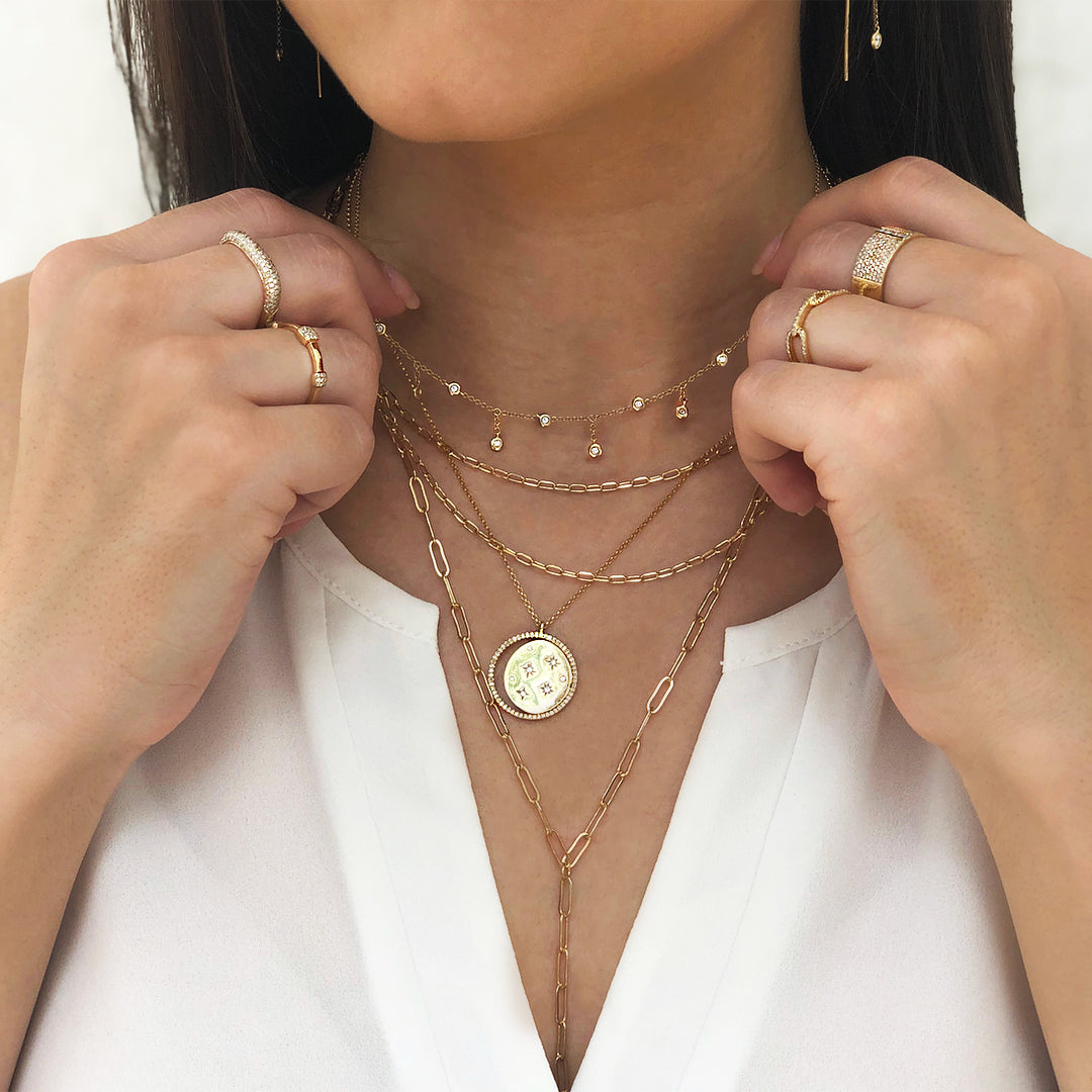 Diamond choker necklace worn atop layered yellow gold chains