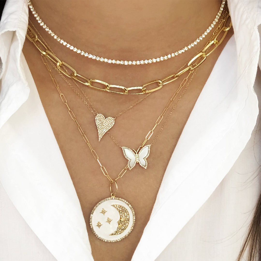 Woman wearing pearl & diamond butterfly necklace layered under yellow gold chain link & diamond necklaces