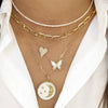 Woman wearing pearl & diamond butterfly necklace layered under yellow gold chain link & diamond necklaces