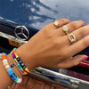 Woman wearing rainbow bead bracelet with colorful bead bracelets and yellow gold rings
