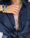 Woman wearing rainbow bead bracelet with yellow gold bracelets and charm necklace
