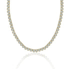 A yellow gold tennis necklace featuring a continuous row of round-cut clear gemstones, displayed against a clean white background with a soft reflection below.