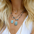Aquamarine Oval Pendant, Blue Topaz Bezel, &amp; Labradorite Wire Chain Necklace

Curated for the jewelry lover who craves texture. This artisanal piece brings together a triad of powerful stones: the tranquil blue of Aquamarine, the sharp clarity of Blue Topaz, and the moody, iridescent depth of Labradorite beads. Wear it to add a sophisticated pop of color to a neutral knit, or layer it with shorter gold chains for a high-impact, tiered look.

Yellow Gold Plated
1.08" Long X 0.60" Wide
16-18" Adjustable L