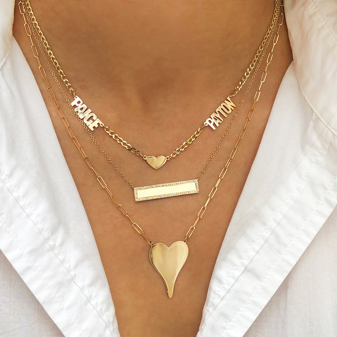 Gold necklaces with heart and bar pendants on a white shirt background