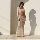 Woman wearing a beige lace outfit standing in front of a white wall with an arch.