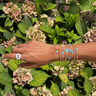 Evil eye ring and  stack bracelet on an arm.