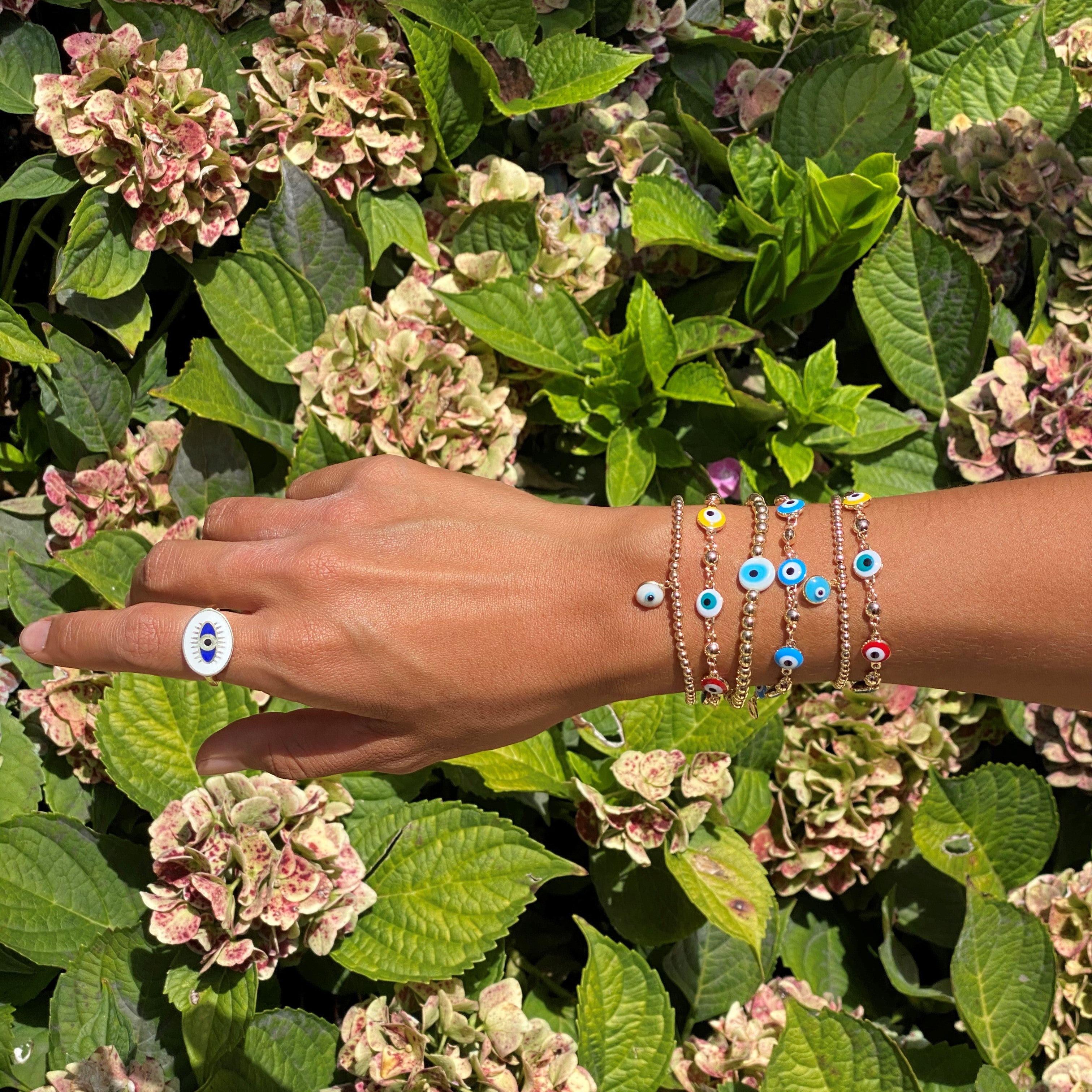 Evil eye ring and  stack bracelet on an arm.