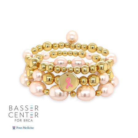 This stunning bracelet features gold beads and faux pink pearls. This gorgeous bracelet perfectly complements any ensemble, making it a versatile addition to your jewelry collection. Pair it effortlessly with other jewels and stay in vogue while making a meaningful impact.  Yellow Gold Beads and Faux Pink Pearls 3 Stretch Bracelet Set  Yellow Gold Plated 0.15", 0.20", 0.22", 0.30" Gold Beads 0.32", 0.40" x 0.50" Faux Light Pink Pearls Breast Cancer Awareness Ribbon Charm