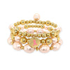 This stunning bracelet features gold beads and faux pink pearls. This gorgeous bracelet perfectly complements any ensemble, making it a versatile addition to your jewelry collection. Pair it effortlessly with other jewels and stay in vogue while making a meaningful impact.  Yellow Gold Beads and Faux Pink Pearls 3 Stretch Bracelet Set  Yellow Gold Plated 0.15", 0.20", 0.22", 0.30" Gold Beads 0.32", 0.40" x 0.50" Faux Light Pink Pearls Breast Cancer Awareness Ribbon Charm