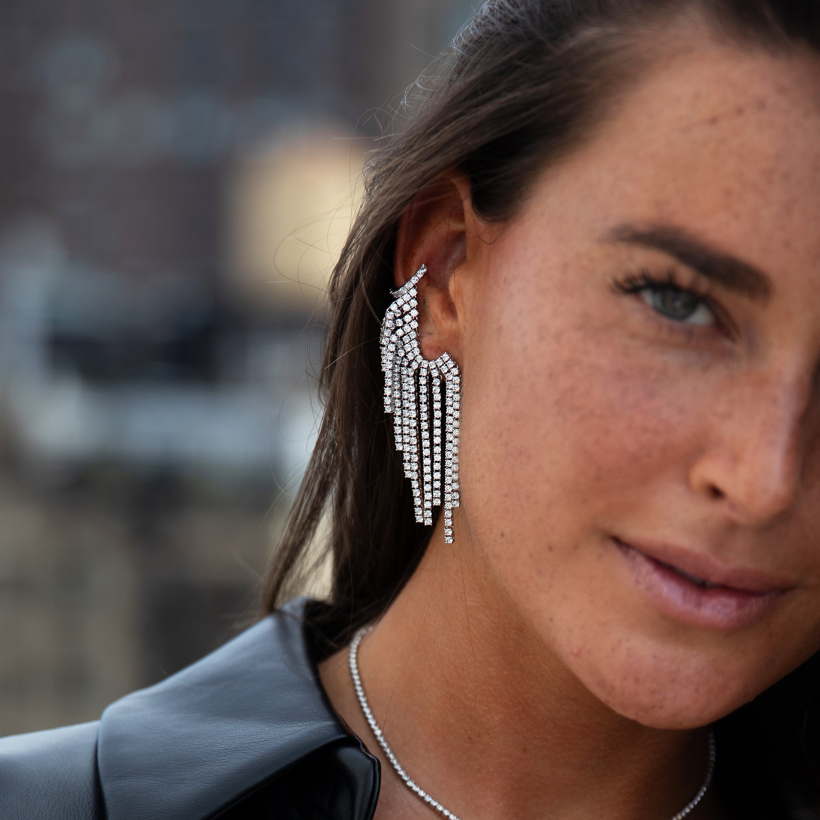 Close-up of a woman wearing sparkling tassel earrings with a blurred background
