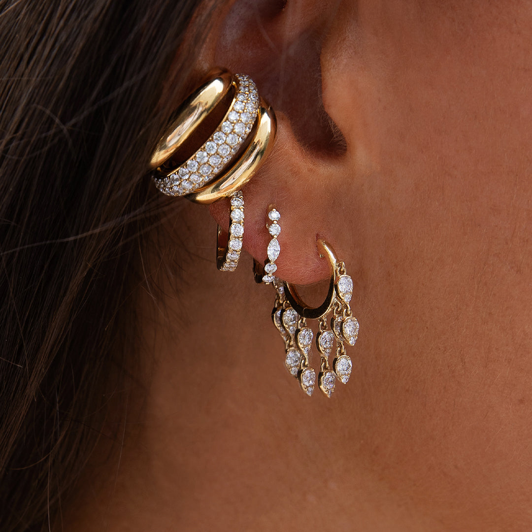 Close-up of a person wearing gold hoop earrings with diamond accents.