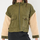 Person wearing a green and beige jacket on a white background