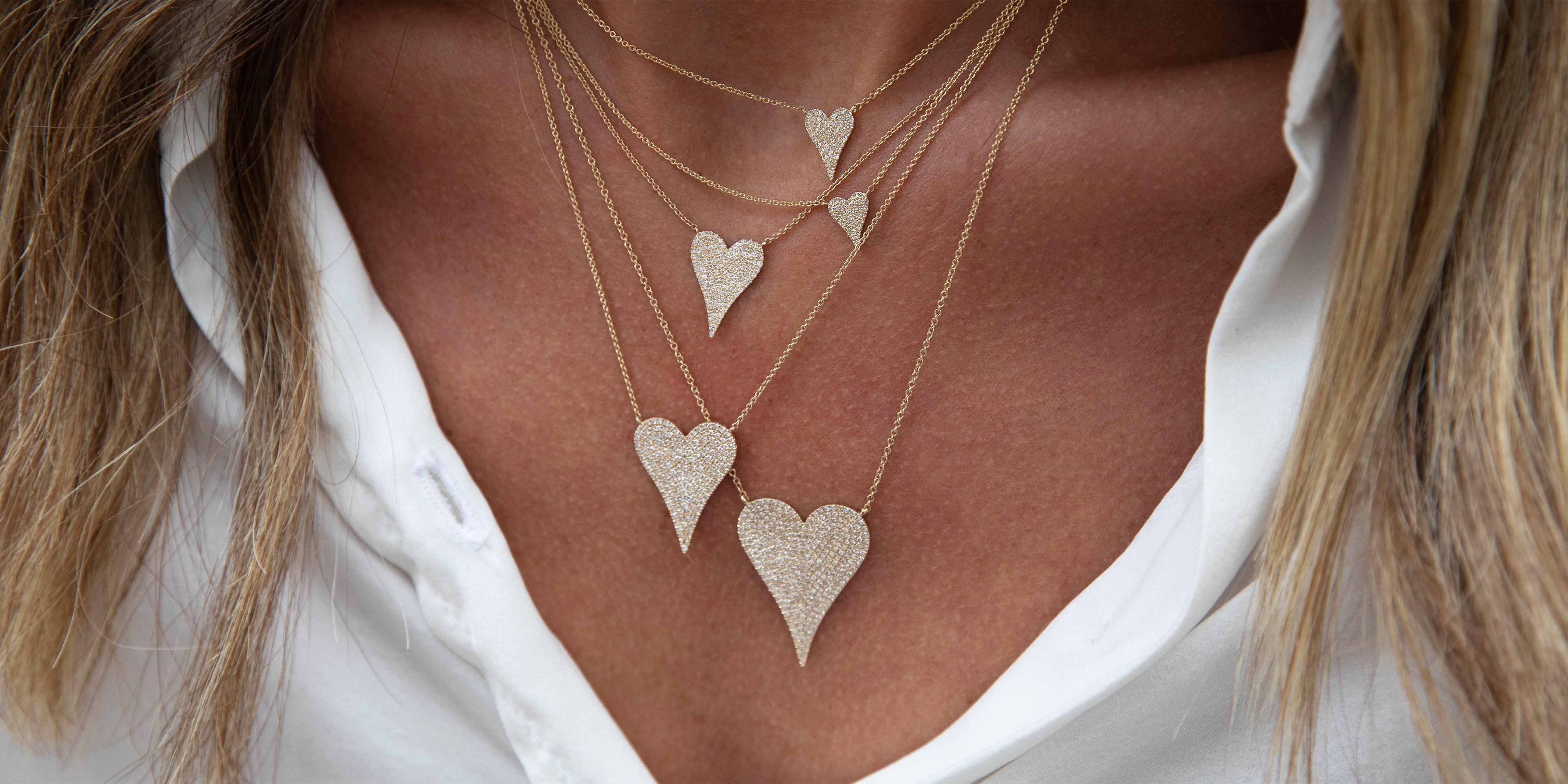Necklace with heart-shaped pendants worn by a person against a white shirt background