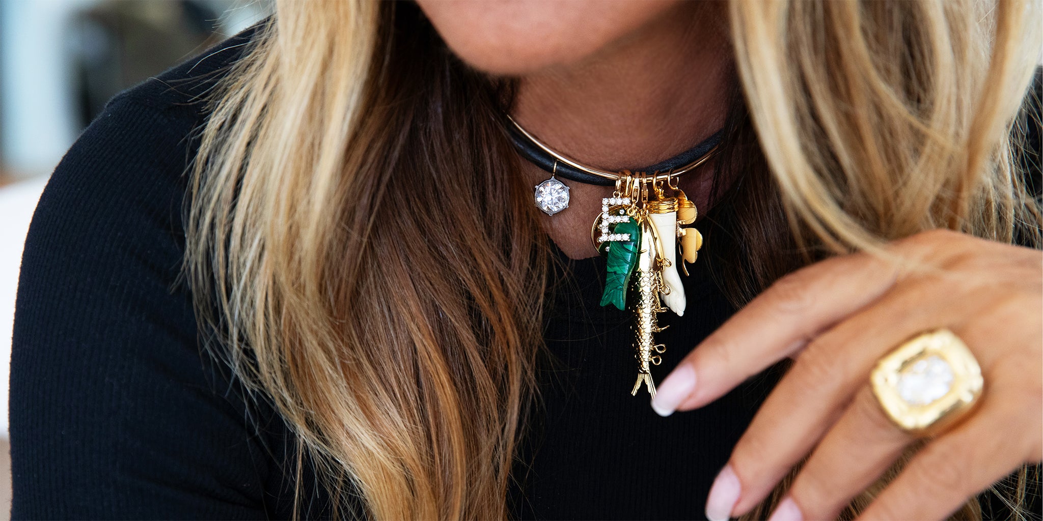 Close-up of a person wearing a black top with a colorful necklace and gold ring.