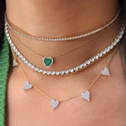 Close-up of layered necklaces with heart pendants on a person wearing a green and yellow garment.