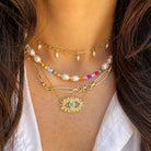 Close-up of a person wearing multiple necklaces with a white shirt.