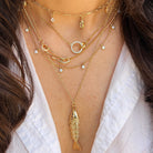 Close-up of a person wearing multiple gold necklaces with a white shirt.