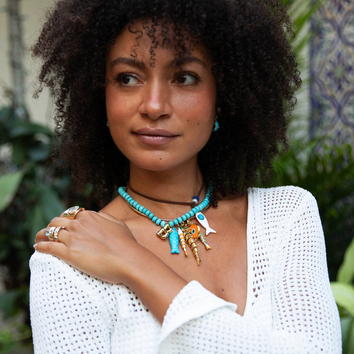 Woman wearing a turquoise necklace with plants in the background