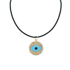 Necklace with a gold and blue evil eye pendant on a black cord against a white background