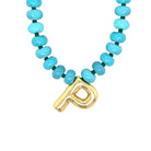 Necklace with turquoise beads and a gold letter 'P' pendant on a white background