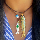 Necklace with two fish pendants on a person wearing a blue and white striped shirt.