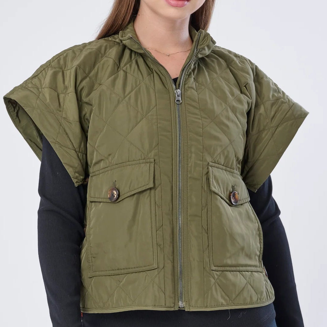 Woman wearing a green vest over a black long-sleeve shirt on a white background