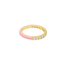 A gold band ring with a half-pink enamel half and a row of clear cubic zirconia stones on the other half, shown on a plain white background.