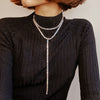 Woman wearing baguette lariat necklace over a dark turtle neck sweater
