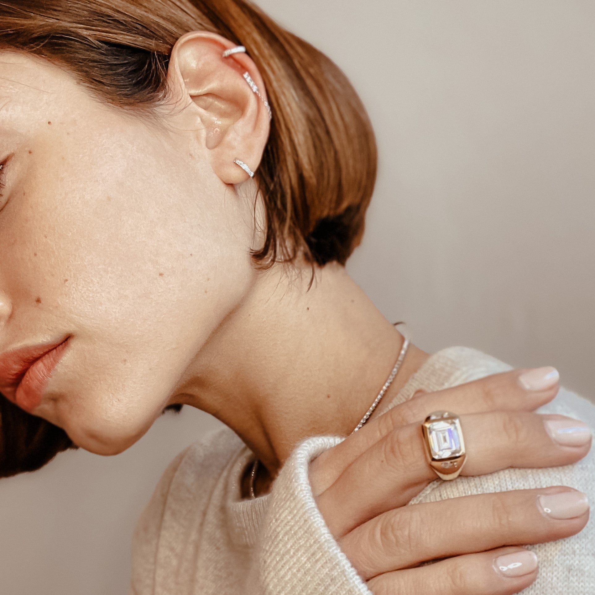 Emerald cut ring worn with pave huggie earrings