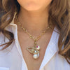 Woman wearing pearl charm on yellow gold chain link necklace with pave eye charm