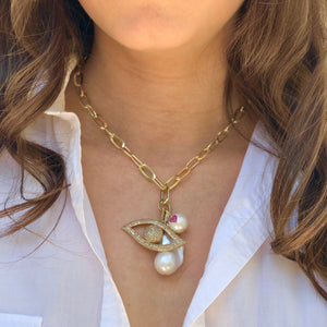 Woman wearing yellow gold chain with eye and pearl charms added