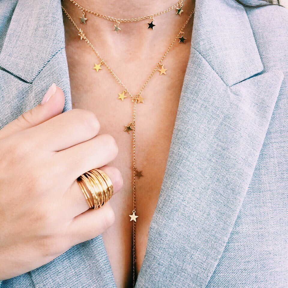 Woman wearing yellow gold cluster ring with star necklaces