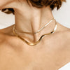 Woman wearing two layered yellow gold herringbone necklaces