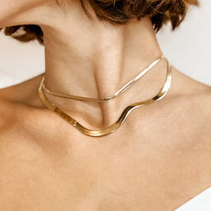 Yellow gold herringbone necklaces layered on woman's neck