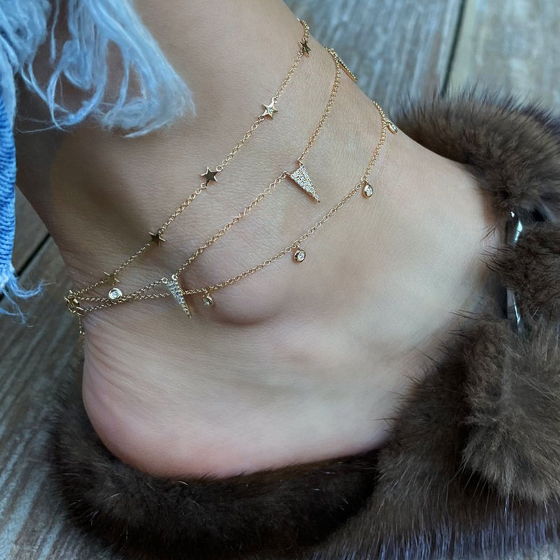 Diamond dangle anklet worn layered with others in yellow gold