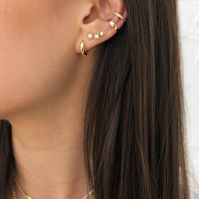 Woman wearing Plain Thick Huggie Pierced Earrings with yellow gold ear cuffs and pave starburst studs